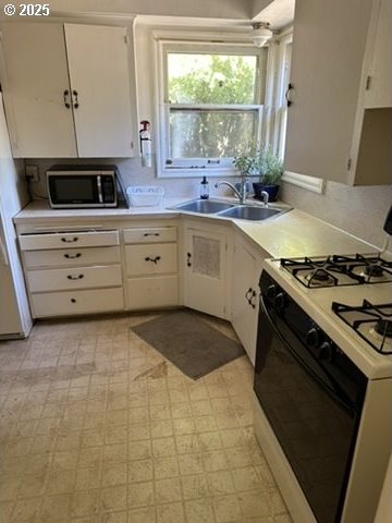 kitchen with a sink, range with gas stovetop, light countertops, light floors, and stainless steel microwave