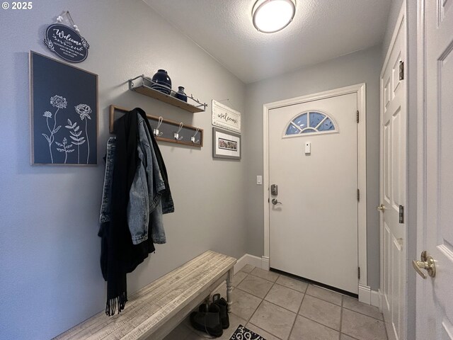 mudroom featuring a textured ceiling, baseboards, and light tile patterned floors