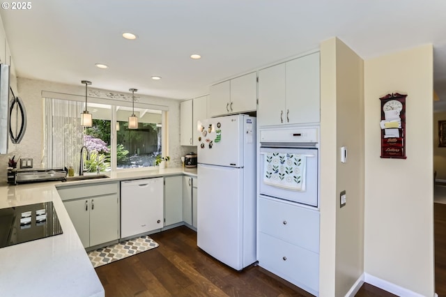kitchen featuring white appliances, a sink, light countertops, dark wood-style flooring, and recessed lighting