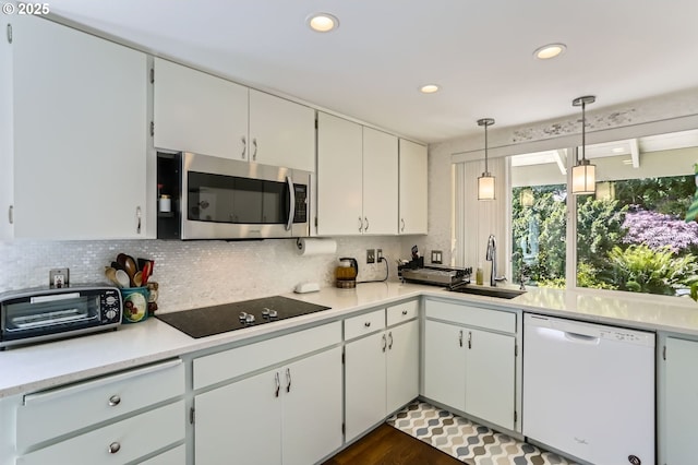 kitchen with white dishwasher, stainless steel microwave, black electric stovetop, a sink, and decorative backsplash