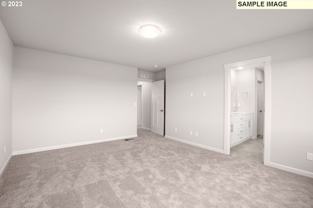 unfurnished bedroom featuring ensuite bathroom and light colored carpet