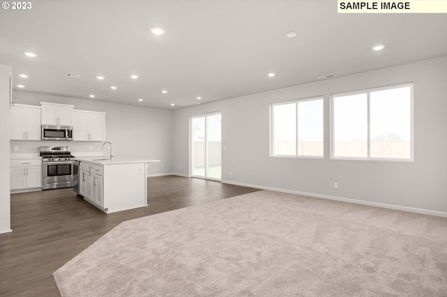 kitchen featuring white cabinets, a center island with sink, sink, appliances with stainless steel finishes, and dark hardwood / wood-style flooring