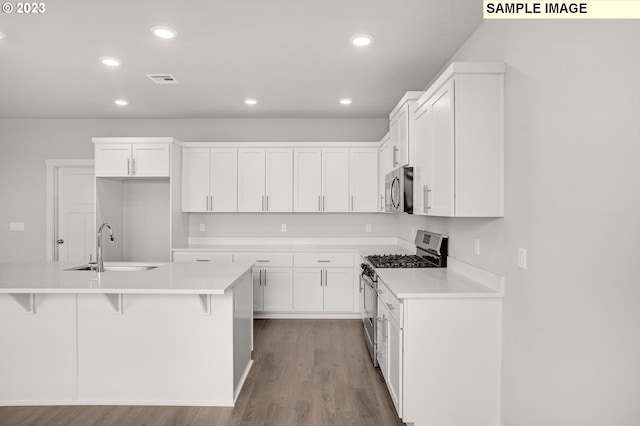 kitchen with white cabinets, stainless steel appliances, a center island with sink, and sink