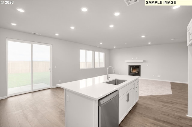 kitchen featuring white cabinetry, sink, stainless steel dishwasher, an island with sink, and light hardwood / wood-style floors