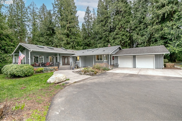 ranch-style house with a porch, an attached garage, a front lawn, and driveway