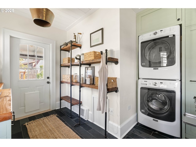 laundry area with baseboards, stacked washer / drying machine, and laundry area