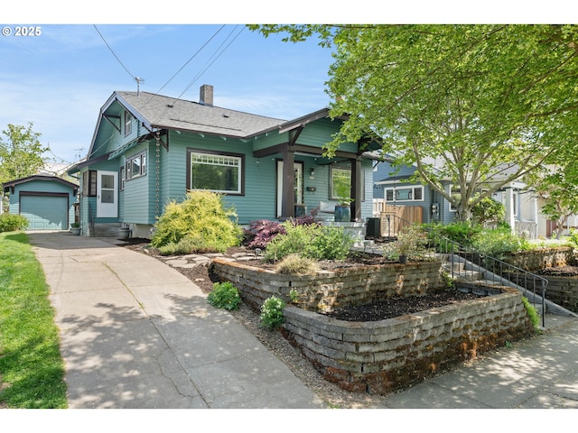 bungalow with an outdoor structure, roof with shingles, a chimney, driveway, and a detached garage