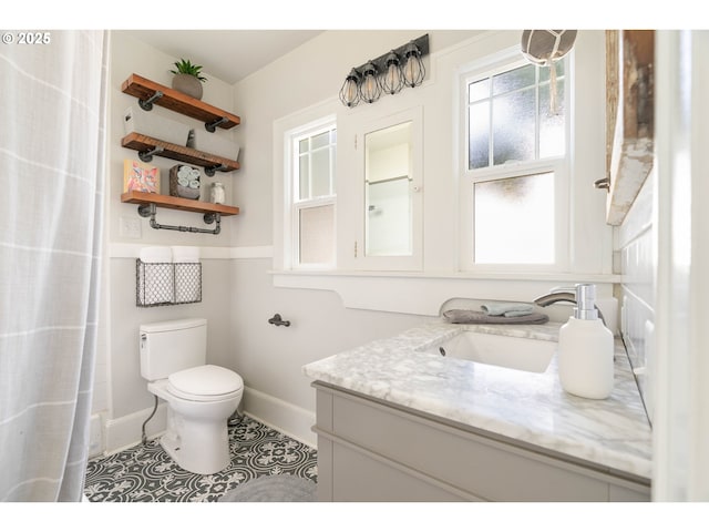 bathroom with baseboards, tile patterned flooring, toilet, and vanity
