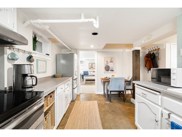 kitchen featuring concrete flooring, light countertops, freestanding refrigerator, under cabinet range hood, and white cabinetry