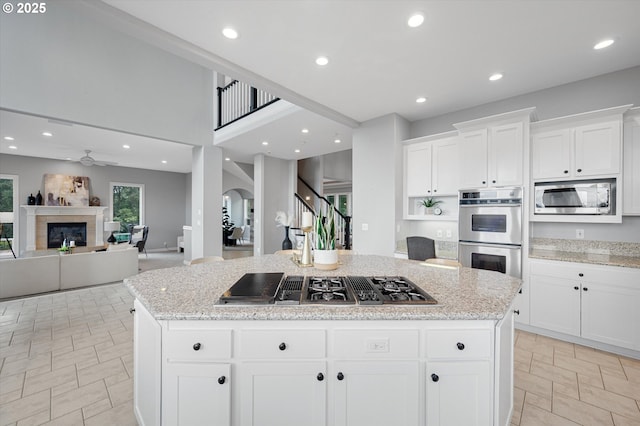 2350 SW Turner Rd, West Linn, OR 97068 - kitchen featuring stainless steel appliances, arched walkways, a ceiling fan, light stone counters, and a center island
