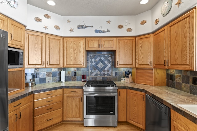 kitchen with stainless steel gas stove, built in microwave, dishwasher, decorative backsplash, and light wood-type flooring