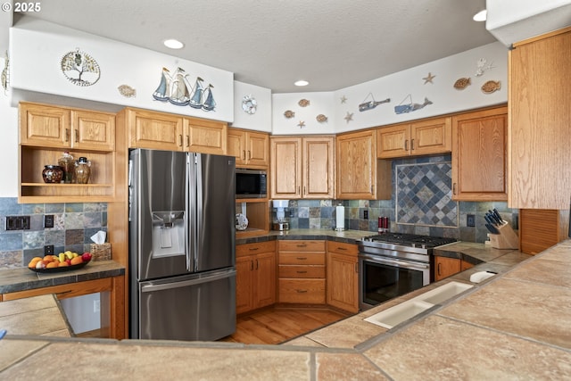 kitchen with decorative backsplash, tile countertops, stainless steel appliances, and a textured ceiling