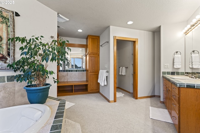 bathroom with vanity, a bath, and a textured ceiling