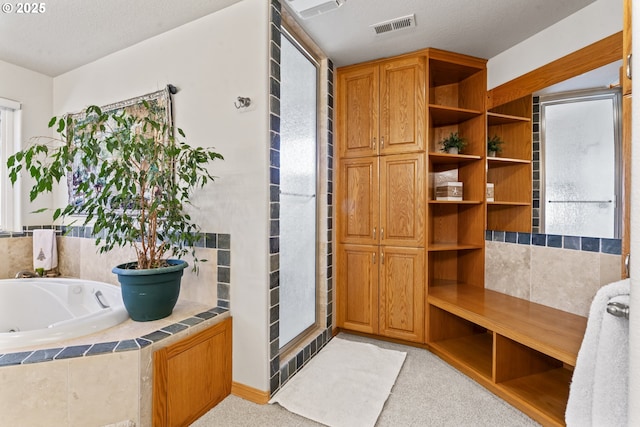 bathroom with tiled tub and a textured ceiling