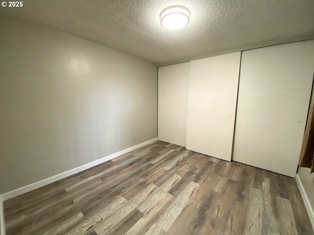 unfurnished bedroom featuring hardwood / wood-style flooring, a closet, and a textured ceiling