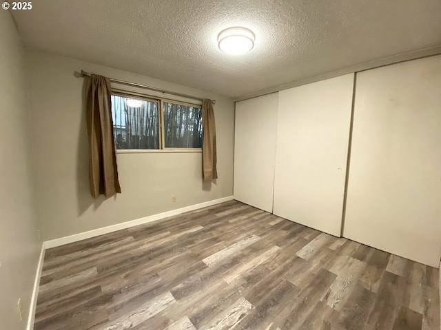 unfurnished bedroom featuring hardwood / wood-style flooring, a closet, and a textured ceiling