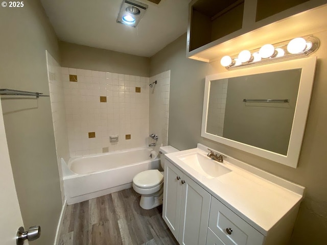 full bathroom featuring vanity, hardwood / wood-style floors, tiled shower / bath combo, and toilet