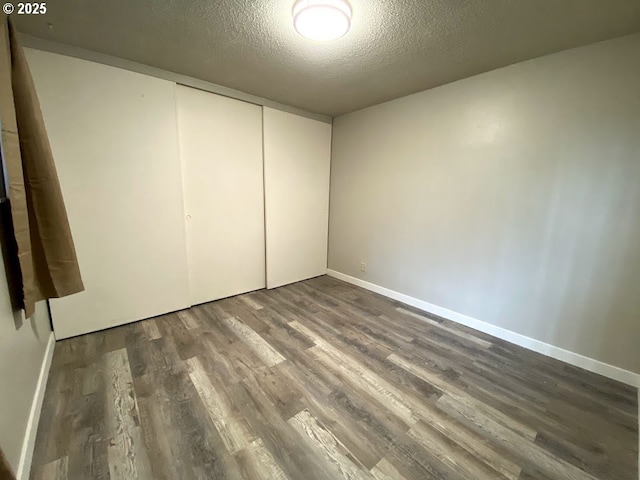 unfurnished bedroom featuring a closet, dark hardwood / wood-style floors, and a textured ceiling