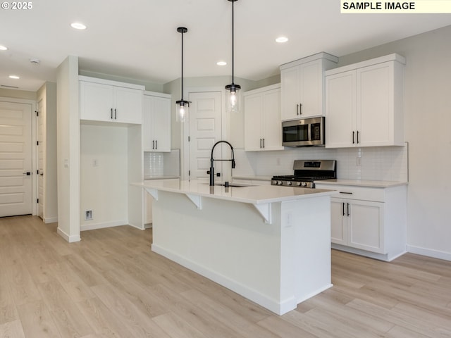 kitchen featuring light wood-style flooring, stainless steel appliances, light countertops, white cabinetry, and a sink