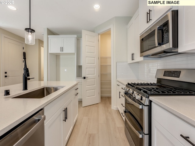 kitchen featuring appliances with stainless steel finishes, a sink, white cabinetry, and tasteful backsplash