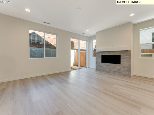 unfurnished living room with recessed lighting, visible vents, wood finished floors, a tile fireplace, and baseboards