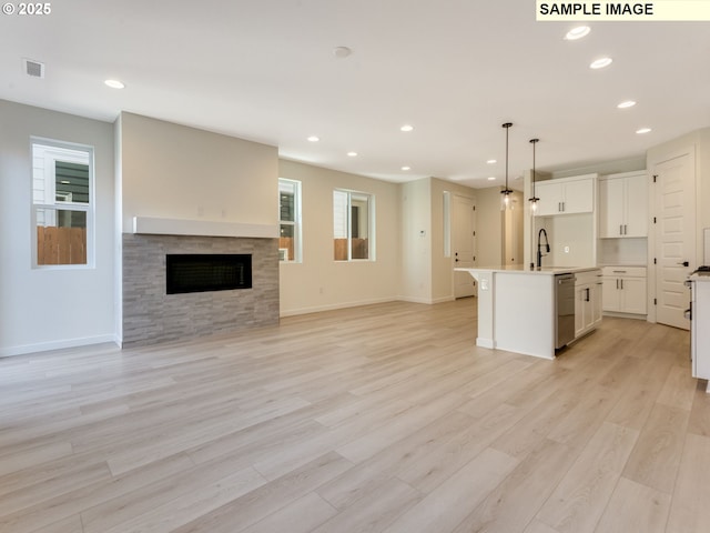 kitchen with a fireplace, a sink, white cabinetry, light wood-type flooring, and dishwasher