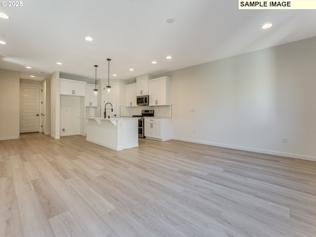 unfurnished living room featuring light wood-type flooring, baseboards, a sink, and recessed lighting