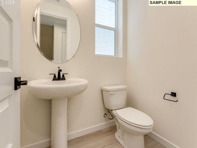 bathroom featuring a sink, wood finished floors, toilet, and baseboards