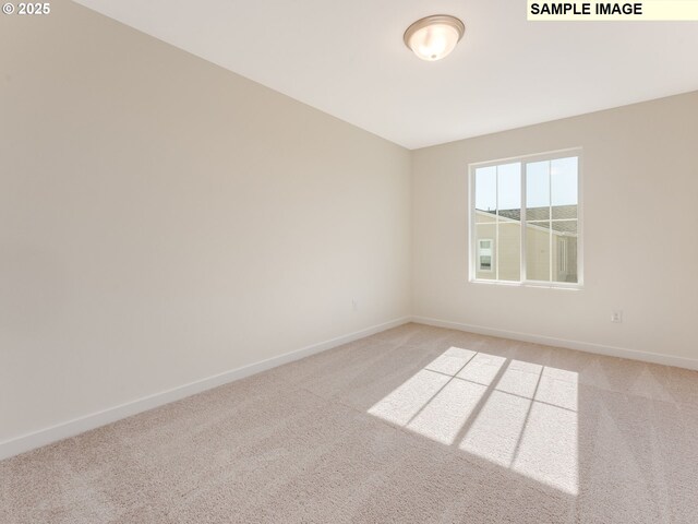 empty room featuring light carpet and baseboards