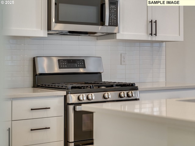 kitchen featuring stainless steel appliances, light countertops, white cabinetry, and backsplash