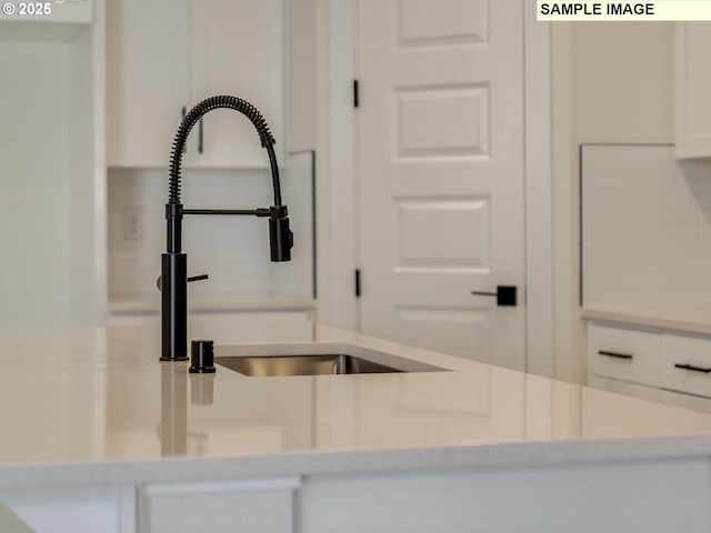 room details featuring light countertops, a sink, and white cabinets