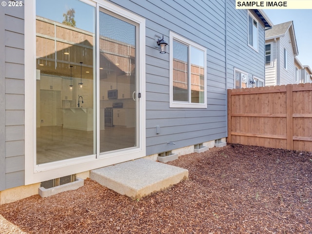 doorway to property with crawl space, fence, and a sink