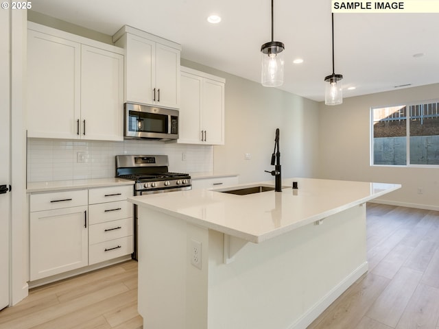 kitchen featuring stainless steel appliances, tasteful backsplash, a sink, and light wood-style flooring