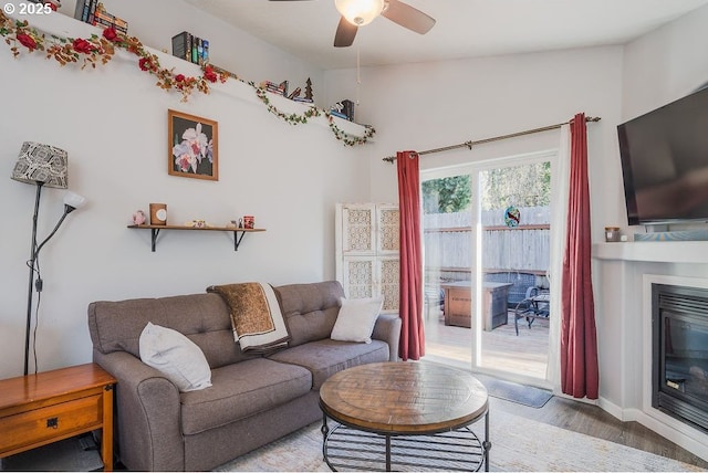 living room featuring ceiling fan, lofted ceiling, and light hardwood / wood-style flooring