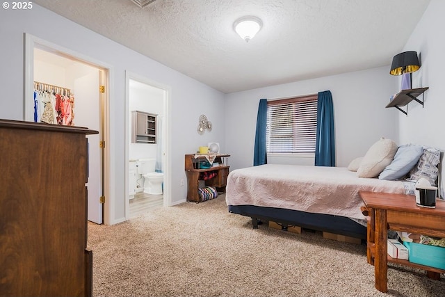 bedroom featuring ensuite bath, a textured ceiling, and carpet flooring