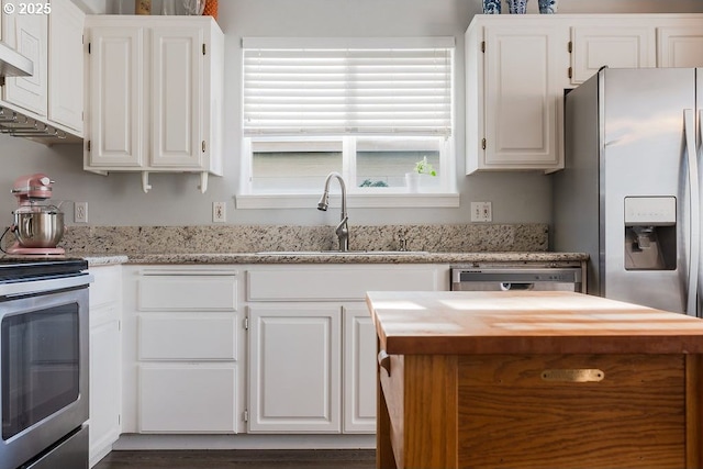 kitchen featuring stainless steel appliances, white cabinetry, light stone countertops, and sink