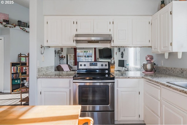 kitchen featuring white cabinets, light stone countertops, and electric range