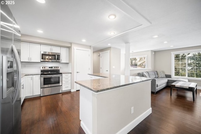 kitchen featuring white cabinetry, appliances with stainless steel finishes, dark hardwood / wood-style floors, and light stone counters