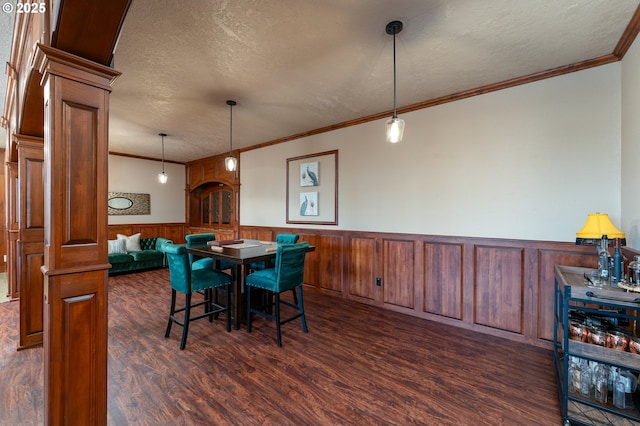 9684 Ankeny Crest Ln S, Salem, OR 97306 - dining room with a wainscoted wall, crown molding, dark wood-type flooring, a textured ceiling, and ornate columns