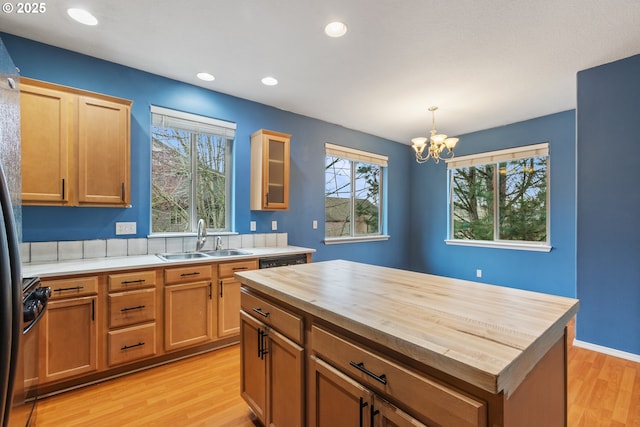 kitchen featuring light wood-type flooring, a sink, wood counters, an inviting chandelier, and hanging light fixtures