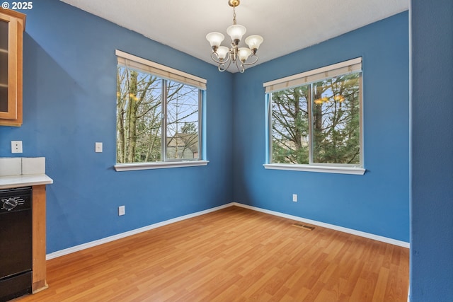 unfurnished dining area with visible vents, baseboards, a notable chandelier, and light wood-style flooring