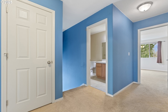 hall with light colored carpet and baseboards