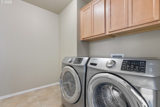 washroom featuring baseboards, cabinet space, light tile patterned flooring, and washer and clothes dryer