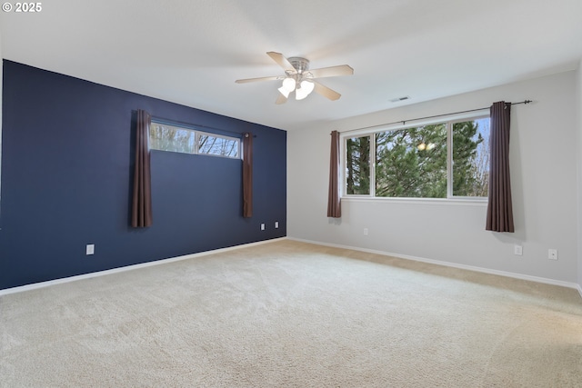 empty room with visible vents, baseboards, a ceiling fan, and carpet flooring