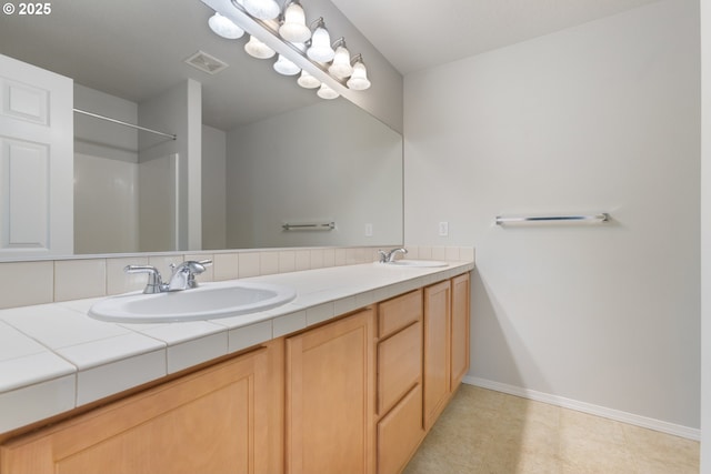 full bath featuring double vanity, visible vents, baseboards, and a sink