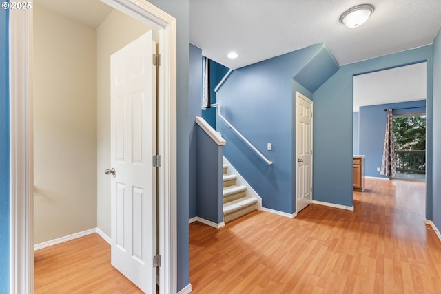 hall with stairway, baseboards, and light wood-style floors