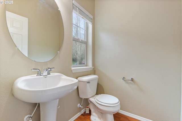 bathroom with a sink, toilet, baseboards, and wood finished floors