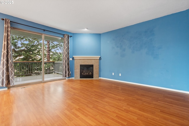 unfurnished living room featuring visible vents, wood finished floors, baseboards, and a tile fireplace