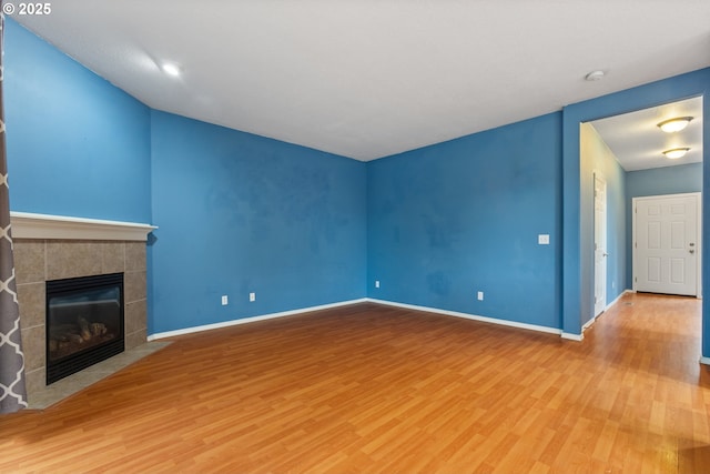 unfurnished living room featuring wood finished floors, baseboards, and a tile fireplace