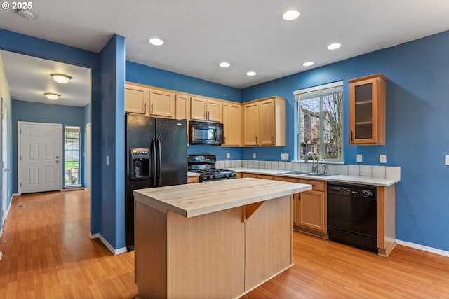 kitchen featuring light brown cabinets, a kitchen island, butcher block countertops, black appliances, and a sink